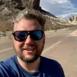 A photo of Alec Lasar wearing sunglasses standing on the side of the road in Big Bend State Park, Texas.